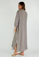 Vestido largo color beige de lino, con mangas largas abullonadas y volantes verticales en el frente. Cierre frontal con botones.