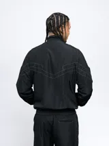 Campera deportiva Umbro de nylon con diseño color block en blanco, azul y rojo. Tiene cuello alto, cierre frontal con cremallera y bolsillos laterales. Logo de Umbro bordado en el pecho.