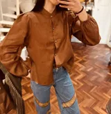 Camisa blanca de lino con cuello mao, mangas largas abullonadas y cierre frontal con botones.