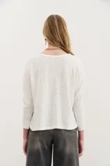 Remera blanca de algodón con calce relajado y cuello redondo. Tiene mangas largas que se ajustan hacia los puños.