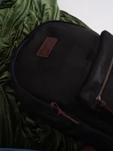 Mochila de cuero color marrón con forro de lino y cierres de bronce. Tiene un compartimento interno acolchado para computadora portátil.