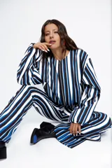 Campera bomber corta con estampado a rayas verticales blancas, negras y azules. Tiene cuello redondo, cierre frontal con cremallera y mangas largas abullonadas.