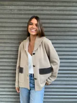 Campera de punto color beige con cuello tipo chal y cierre con tres botones. Tiene dos bolsillos frontales con solapa de cuero marrón.