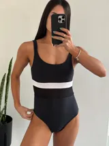Traje de baño entero negro con banda horizontal blanca a la altura del busto.