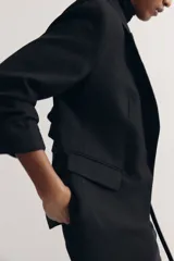 Blazer negro entallado confeccionado en mezcla de viscosa, con hombreras, solapas de muesca, mangas tres cuartos fruncidas y bolsillos delanteros con solapa. Sin cierre.