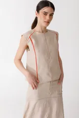 Blusa color ladrillo de lino 100% con cuello redondo y sin mangas. Presenta vivos y pespuntes a contratono en color marrón.