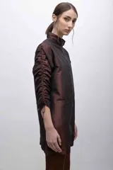Vestido marrón de tafeta tornasolada con cuello alto y cierre frontal. Mangas largas con sistema de frunce ajustable.