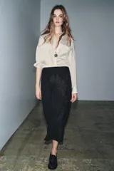 Falda larga negra de tiro medio confeccionada en hilatura con mezcla de algodón. Detalle de bordados florales a tono. Bajo evasé y cierre con cremallera oculta en costura.