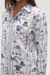 Camisa de manga larga con estampado de motivos playeros en tonos marrones sobre fondo beige, cuello camisero y cierre frontal con botones.