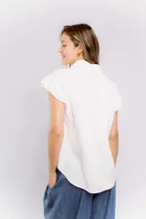 Camisa blanca de mangas cortas con volados y bordado de flores en el frente.