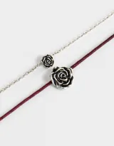 Set de dos collares cortos, uno con cadena plateada y dije de rosa plateada, y otro con cordón color borgoña y dije de rosa plateada.