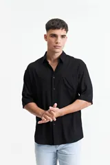 Camisa negra oversize de manga corta con cuello clásico y bolsillo en el pecho.