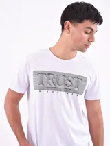 Remera blanca de corte slim fit con estampado frontal de líneas horizontales negras que forman la palabra 'Trust' y la frase 'In Yourself'.