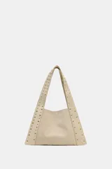 Bolso bandolera color beige de piel serraje, con tachuelas metálicas doradas en el cuerpo y las asas. Tiene doble asa de hombro, bolsillo interior y cierre con botón imantado.