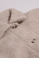 Saco de sherpa color beige, con cuello camisero, cierre con botones y bolsillos laterales.
