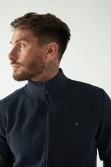 Campera negra de felpa con cierre frontal, bolsillos laterales, puños y logo bordado en el pecho.