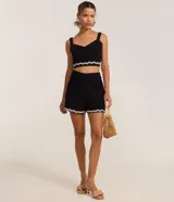 Conjunto de crop top y shorts negros con ribete de ondas blancas. El top tiene breteles anchos y escote en V. Los shorts son de tiro alto.