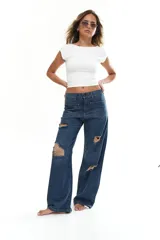 Pantalón jean azul oscuro de corte ancho con roturas y bolsillos delanteros.