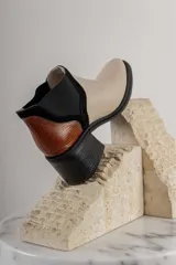 Bota corta de cuero sintético negro con elástico lateral y detalle de estampado animal print en el talón.