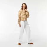 Chaqueta corta acolchada color beige con estampado abstracto en blanco, cuello redondo y cierre frontal con botones.