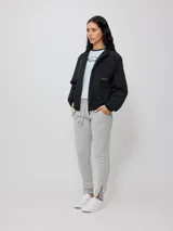 Pantalón deportivo tipo jogging color negro, confeccionado en 60% algodón y 40% poliéster, con cintura elástica ajustable con cordón, bolsillos laterales y puños ajustados con cierre en los tobillos.