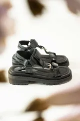 Sandalias con plataforma color marrón, con tiras de cuero color blanco y marrón con hebillas metálicas.