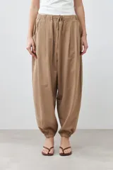 Pantalón tipo barrel color tostado, confeccionado en lino, con cintura elástica y cordón ajustable.