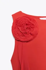 Top negro de cuello redondo y sin mangas, con detalle de flor con volumen en el hombro.