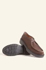 Zapato tipo wallabee de gamuza azul con costuras blancas a la vista y suela de goma negra con plataforma.