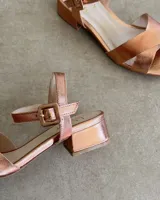 Sandalias bajas negras con tiras finas cruzadas y tobillera con hebilla.