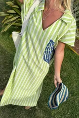 Túnica larga con cuello tipo camisa, de lino a rayas verticales verdes y blancas, con bordado azul en el frente.