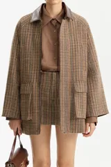 Chaqueta corta de lana con estampado pata de gallo en tonos marrones y verdes, cuello de cuero marrón oscuro y cierre frontal.