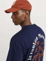 Remera azul marino de algodón con cuello redondo y corte holgado. Estampa en la espalda con diseño de planta en color naranja y texto en blanco.