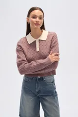 Sweater de tejido de punto con trenzas, color malva/rosado, de corte cropped y manga larga. Presenta cuello polo con solapas en color crema y cierre frontal de botones.