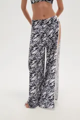 Pantalón largo de calce bajo con estampado abstracto en blanco y negro, y aberturas laterales con ribete blanco.