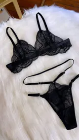Conjunto de lencería compuesto por bralette de encaje negro con breteles regulables y tanga regulable con doble tira a la cintura.