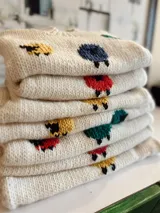 Sweater de lana color crema con cuello redondo y diseño de ovejas de colores bordadas a mano.