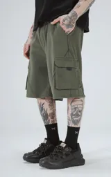 Bermuda de algodón rústico color verde militar, calce oversize, con elástico en la cintura y bolsillos cargo con cierre.