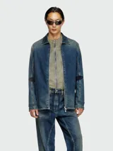 Campera de denim de lavado medio, con cuello camisero y cierre frontal. Presenta detalles de costuras marcadas y parches oscuros en los hombros.