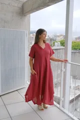 Vestido de manga corta, color rojo oscuro (bordeaux), con escote en V y corte acampanado que termina en un bajo asimétrico con detalle deshilachado.