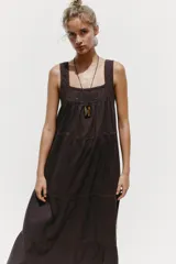 Vestido midi color marrón oscuro, con tirantes anchos y escote recto. Presenta detalle de puntilla en el escote y bordados a tono en el ruedo.