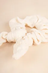 Gomita de pelo tipo scrunchie de textura suave en color blanco.