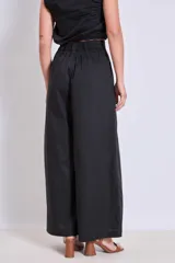 Pantalón negro de tiro alto y corte palazzo, con detalle de strass plateado en forma de ondas verticales.