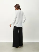 Blusa blanca de manga larga con escote en V y textura arrugada.