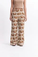 Pantalón wide leg estampado con diseño de conchas marinas color marrón sobre fondo blanco.