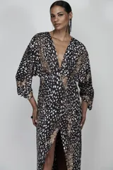 Vestido largo de jersey con estampado animal print en tonos negro, blanco y dorado. Tiene escote en V profundo, mangas 3/4 amplias y abertura frontal en la falda.