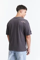 Remera gris oscuro de manga corta con corte boxy, cuello redondo y logo estampado en el pecho.