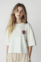 Remera color crudo de corte cropped con estampado pequeño en el pecho.