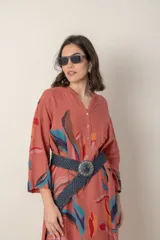 Vestido largo de lino color verde militar con estampado de hojas en tonos azul, naranja y marrón. Tiene cuello mao con botones, mangas tres cuartos y un bolsillo en el pecho.