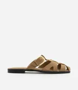 Sandalia plana color beige, tipo mule fisherman, con tiras trenzadas, hebilla lateral y suela negra.